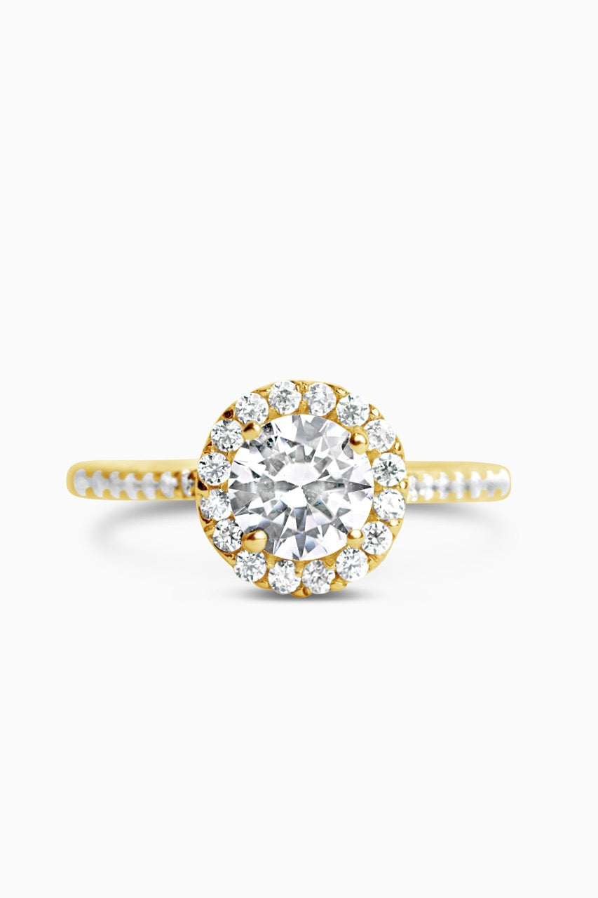 Yellow Gold Round Cut Stone set on a Low Profile Setting with a Halo and Pavé Band